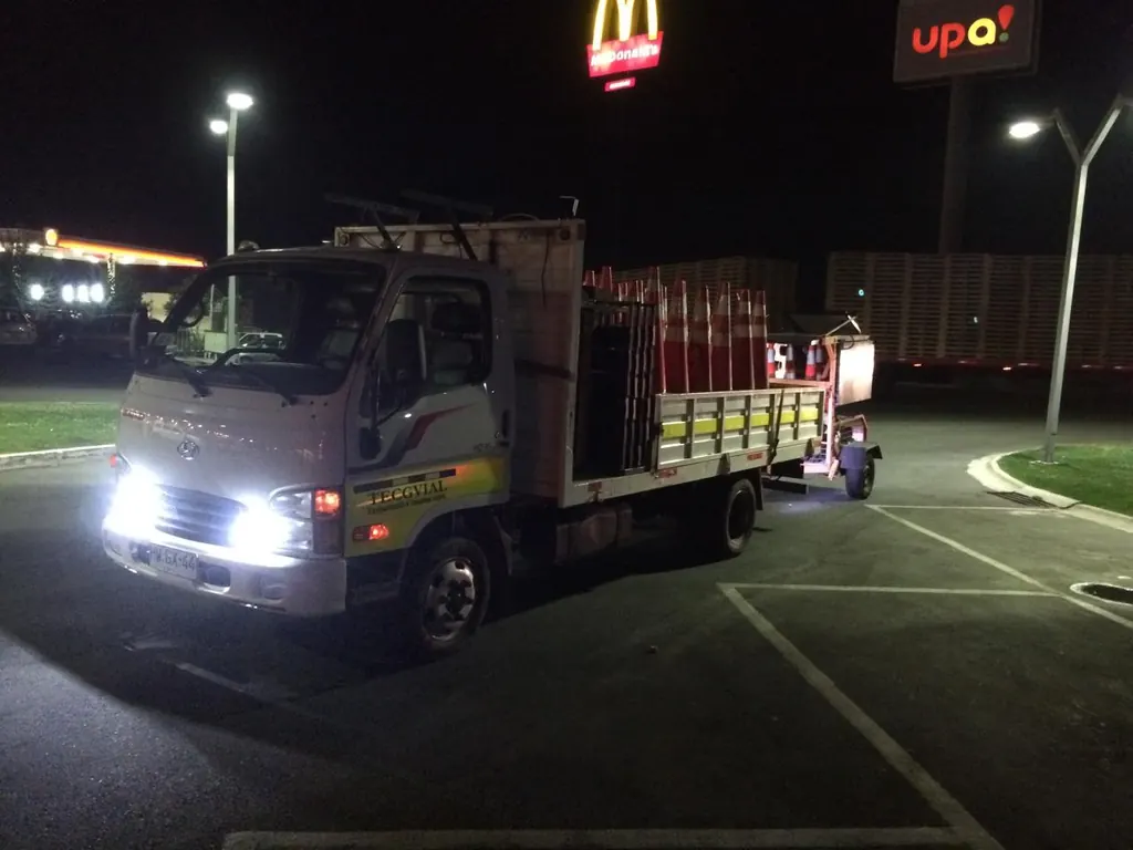 Camión cargado con conos de seguridad durante una faena de control de tránsito nocturna.