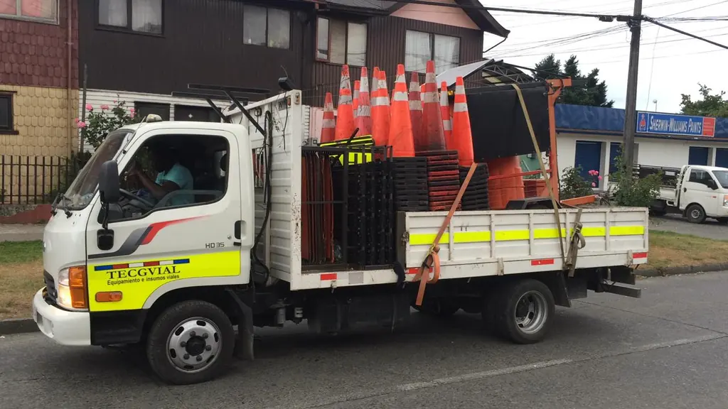 Camión de la flota TECGVIAL con conos apilados y baliza, estacionado antes de un turno de noche.