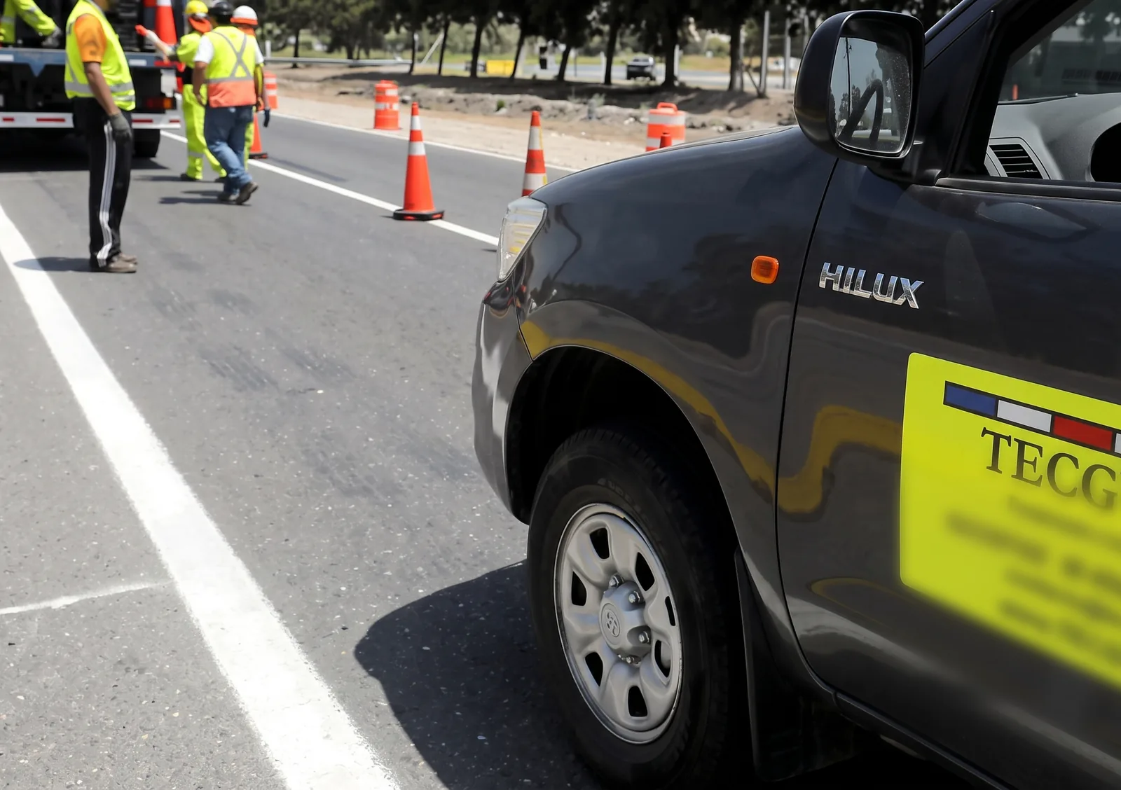 Camioneta rotulada TECGVIAL estacionada en la berma mientras la cuadrilla trabaja en la calzada.