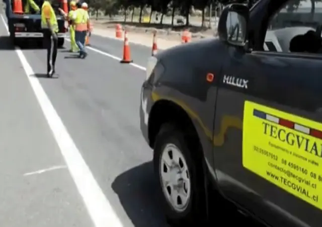 Camioneta rotulada TECGVIAL estacionada en la berma mientras la cuadrilla trabaja en la calzada.