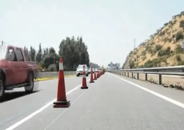 Cierre de pista con conos naranjos sobre una carretera de doble calzada, con vehículos circulando por la pista habilitada.